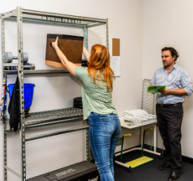 A person demonstrating their manual handling skills whilst a man assesses their technique to avoid gettinginjured at work 